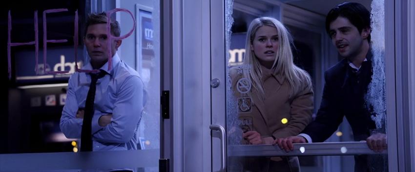 ATM (1970) Movie scene: David (Brian Geraghty), Emily (Alice Eve), and Corey (Josh Peck) inside an ATM booth with frost-tinted windows and the word 'HELP' written on the glass