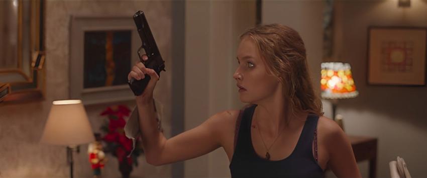 Better Watch Out (1970) Movie scene: Ashley (Olivia DeJonge) holds a gun, cautiously navigating the house during the tense home invasion