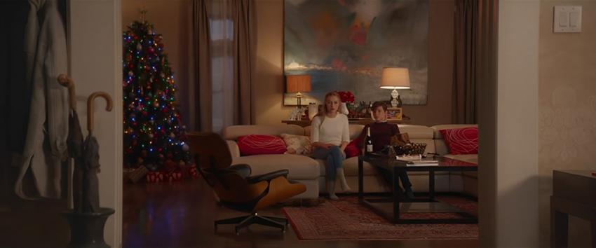 Better Watch Out (1970) Movie scene: Ashley (Olivia DeJonge) and Luke (Levi Miller) sit on the couch, viewed from the hallway