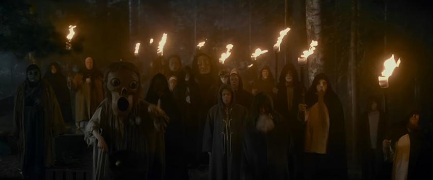 Get Away (1970) Movie scene: A group of people dressed in dark, hooded cloaks stands in a dimly lit forest at night, holding torches