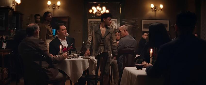 House of Spoils (1970) Movie scene: Chef (Ariana DeBose) stands in the middle of the bustling restaurant, wearing dirty clothes, as she spits something out