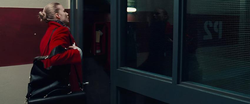 P2 (1970) Movie scene: Angela (Rachel Nichols) exits the office building into the parking garage, with the words 'P2' reflected on the window.