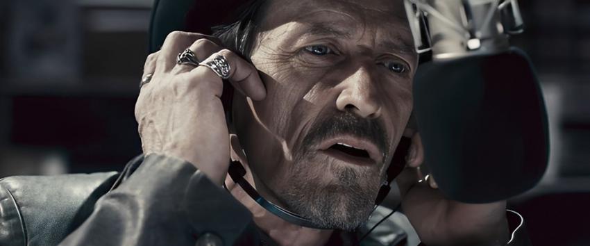 Pontypool (1970) Movie scene: Grant Mazzy (Stephen McHattie) listens intently while wearing headphones, positioned in front of the microphone