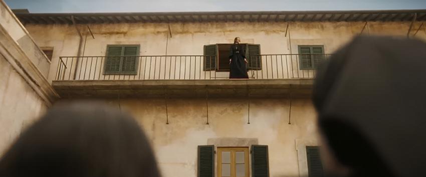 The First Omen (1970) Movie scene: A tense shot looking up at a sister standing on the open edge of a balcony, with onlookers below.
