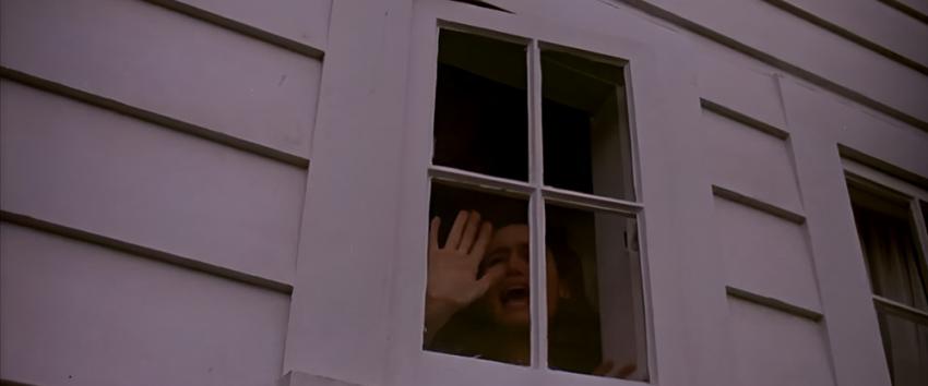 The Stepfather (1970) Movie scene: Stephanie (Jill Schoelen) frantically bangs on an upstairs window, seen from outside, trapped and desperate to escape.