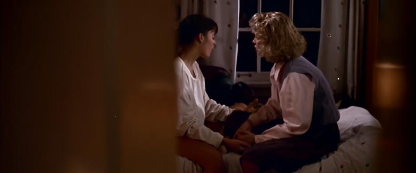The Stepfather (1970) Movie scene: Stephanie (Jill Schoelen) and her mom, Susan (Shelley Hack), sit on the bed in discussion, seen through a partially open door.
