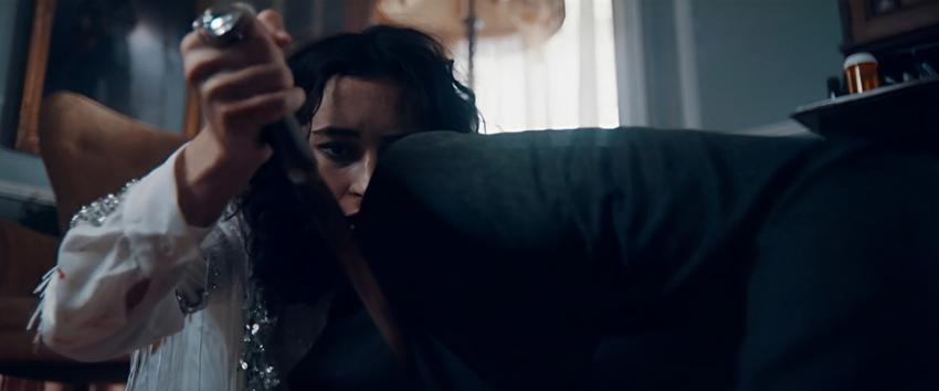 Torn Hearts (1970) Movie scene: Jordan (Abby Quinn) crouched down, hand on a knife lodged in something